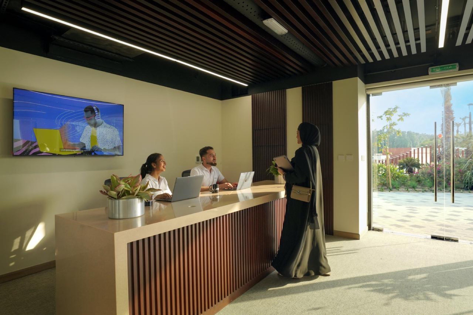 A member checking in at a partner venue's reception desk, staff behind laptops, a Letswork screen on the wall.