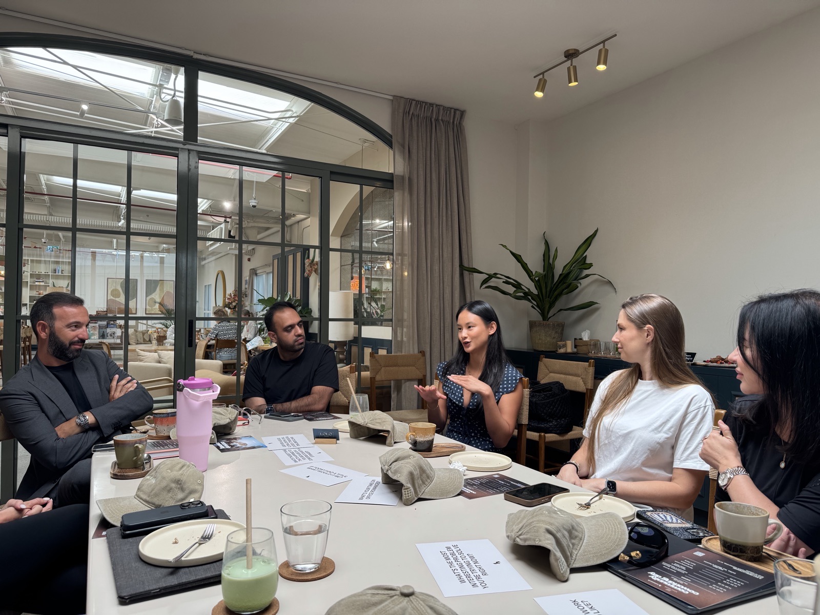 A Letswork community coworking day: five members around a table mid-conversation in a bright café space.